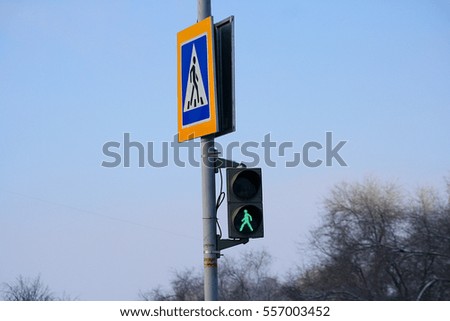 Road pole with a sign and pedestrian traffic lights green light