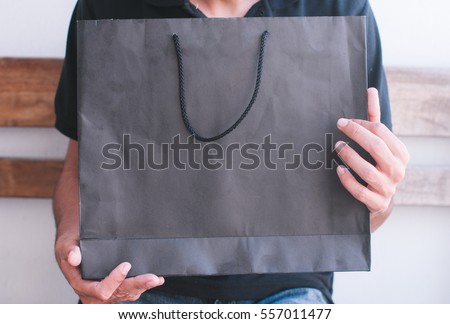 boy holding a black paper bag Royalty-Free Stock Photo #557011477