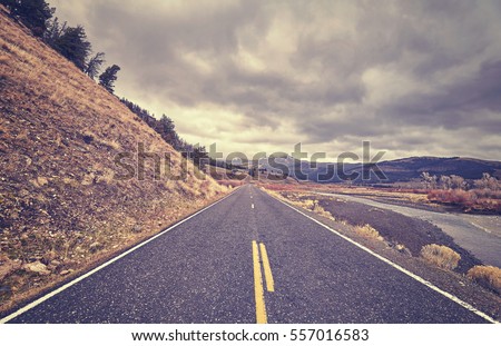 Vintage toned scenic road with stormy clouds, travel concept.