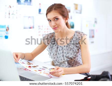 Young woman photographer processing pictures sitting on the desk