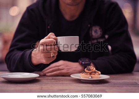Man holding cups of coffee with dessert and smart phone on the table.Cafe shop.Vintage.