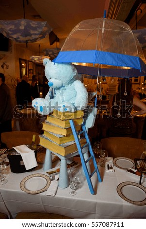 Blue Teddy-bear sits on the heap of books on dinner table