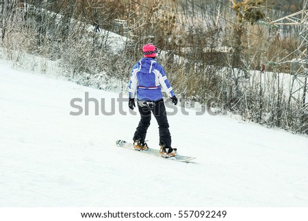 Girl on a snowboard going down the mountain.