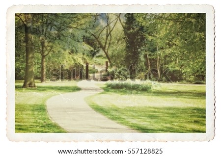 Pathway in a park leading to a forested area. Old photograph look with cracked borders, grain, soft focus all added for effect. 
