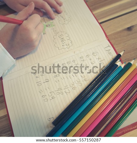 Child Draws Pictures In School Math Notebook