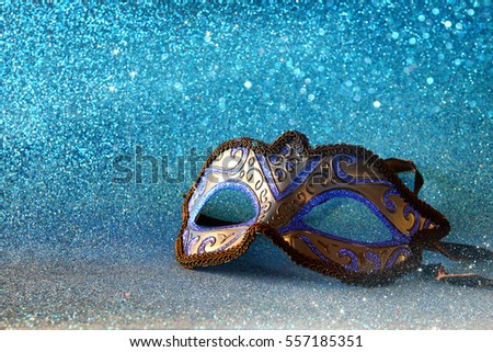 Image of elegant venetian mask on blue glitter background