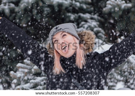 Winter fashion. Portrait of a beautiful happy young woman in warm clothes outdoor showing tongue.