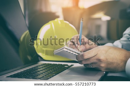 Construction worker contractor in Construction industry is taking note on computer. Modern Engineer  is working in office.  Royalty-Free Stock Photo #557210773