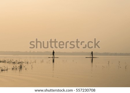 oar padding boat in middle of the lake in silhouette 
