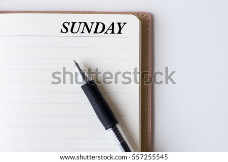 Conceptual,notebook on a white table. open diary and pen with SUNDAY words
