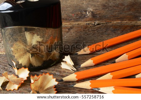 A close up image of several sharpened pencils and a pencil sharpener.