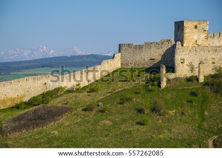 Wall and tower of Spis Castle - Spissky hrad, National Cultural Monument (UNESCO), Slovakia at summer sunny day with picturesque snowcovered peaks of Tatra mountains in background