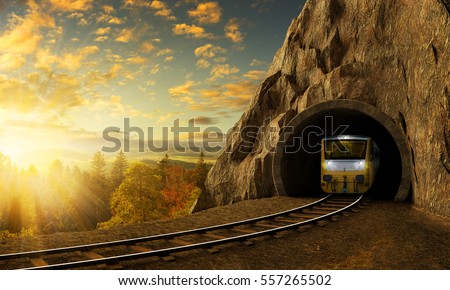 Mountain railroad with train in tunnel. Sunset landscape under the big rock. Royalty-Free Stock Photo #557265502