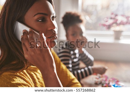 Mother talking on phone forgetting child that sits staring in background