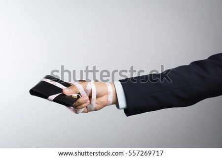 Business man with wallet wrapped by measuring tape on white background