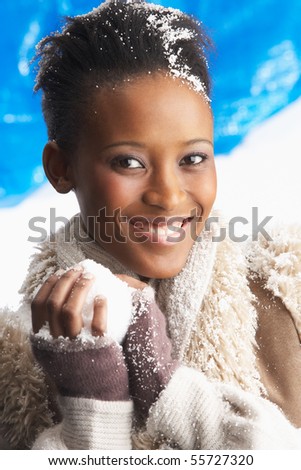 Young Woman Wearing Warm Winter Clothes Holding Snowball In Studio