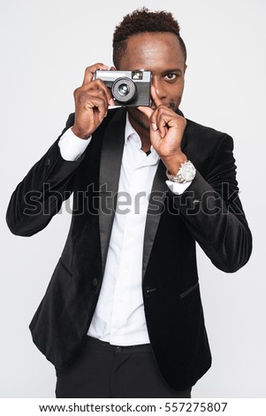 Image of attractive young african businessman make a photo by his camera. Isolated over white background.