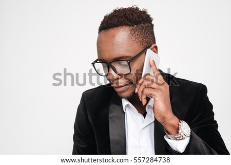 Picture of handsome young african businessman talking by phone. Isolated over white background. Look aside.