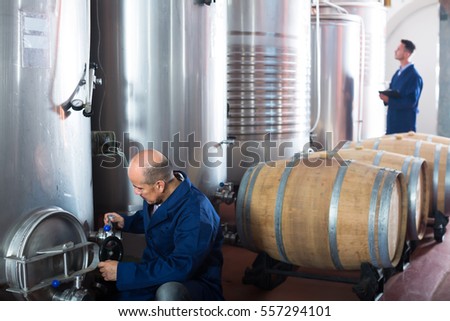 Glad man machinery operator working on secondary fermentation equipment in winery manufactory