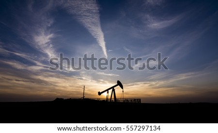Silhouette of crude oil pump in the oilfield at sunset 