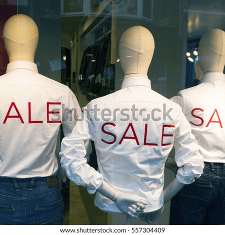 square picture of male fashion dolls with jeans and the word sale printed on white shirts in red letters