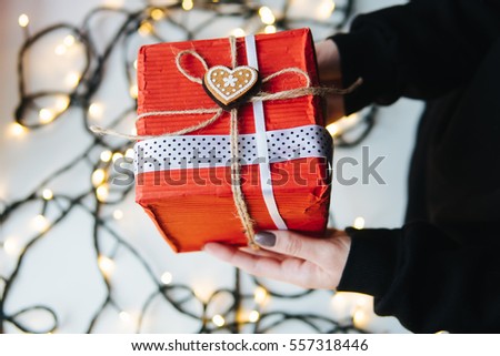 girl holding a Christmas gift in hand on the background of garlands