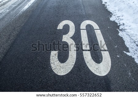 speed limit sign on a tarmac road with snow and ice