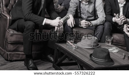 Whiskey, cigar and money on a table with gangster, Mafia counting money Royalty-Free Stock Photo #557326222