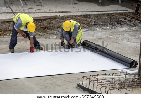 Preparing for foundation waterproofing installation at construction site.  Royalty-Free Stock Photo #557345500