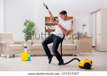 Man cleaning home with vacuum cleaner Royalty-Free Stock Photo #557357497