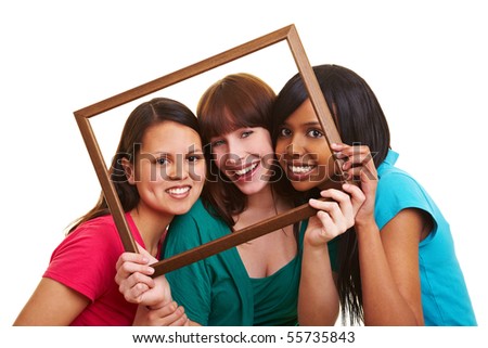 Three young beautiful women looking through an empty frame