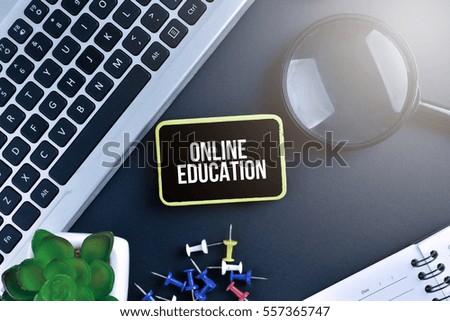 Keyboard with magnifying glass on black background with text ONLINE EDUCATION