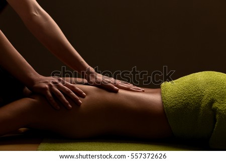 close-up masseur hands doing back massage in spa center. low key photo Royalty-Free Stock Photo #557372626