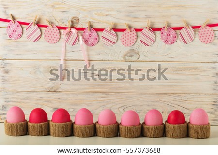 Easter eggs and Easter decor, paper eggs with a pink ribbon on a light wooden background. Selective focus.
