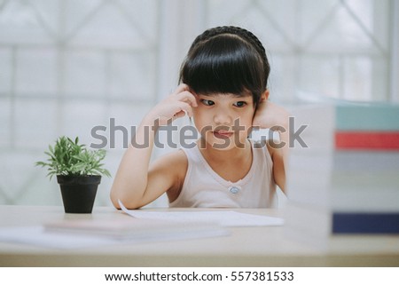 Decent school child. holding her head with a hand and reading a book