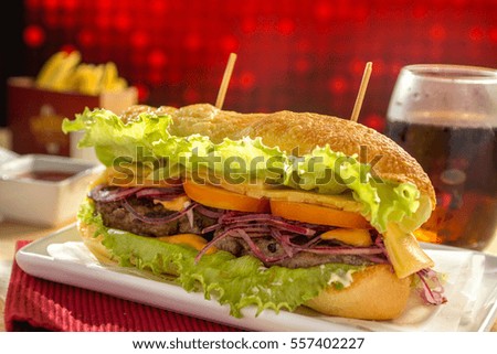 Hamburger with fries on wooden table. Cheeseburger on fresh buns with succulent beef patties and fresh salad ingredients served with French Fries
