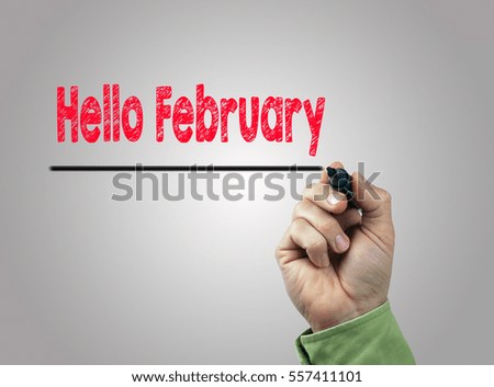 Hello February. Hand with marker writing, light gray background 