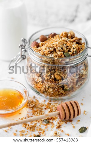 Food background of fresh baked homemade granola in bowl with bottle of milk and honey on white table for healthy breakfast