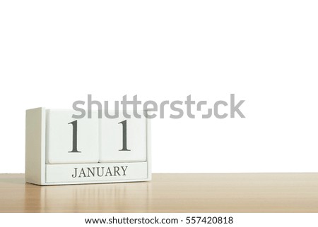Closeup surface white wooden calendar with black 11 january word on blurred brown wood desk isolated on white background with copy space , selective focus at the calendar