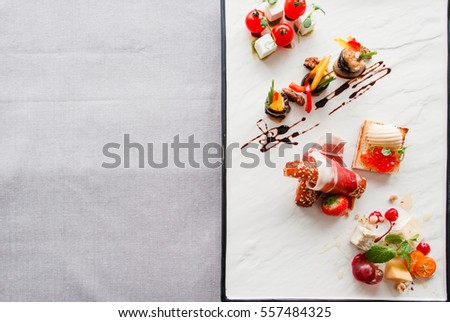 Appetizers mix flat lay, free space for text. Dish with delicatessen variety on half of picture, blank table part. Restaurant menu, recipe, event organization, creativity concept