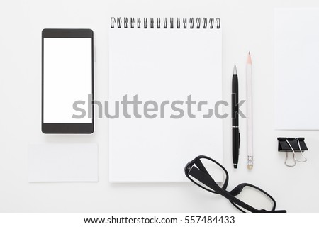 Blank notepad with smartphone and glasses flat lay. Top view on black and white stationery with mobile phone and spectacles. Art, business, creation, imagination, office supplies concept