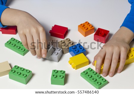 Child's hands and colorful toy building cubes. Top view