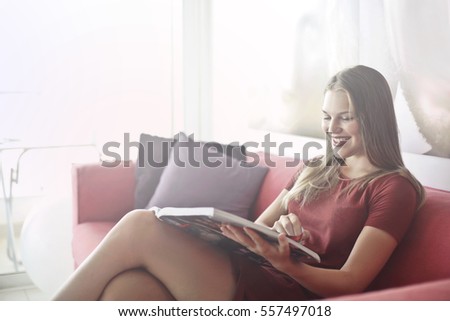 Beautyful young girl looking at a catalogue on the sofa 