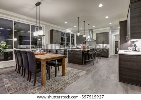 Luxury New construction home with open floor plan: dining and kitchen design. Rustic wood dining table matches with modern style leather chairs. Kitchen accented with dark cabinetry. Northwest, USA