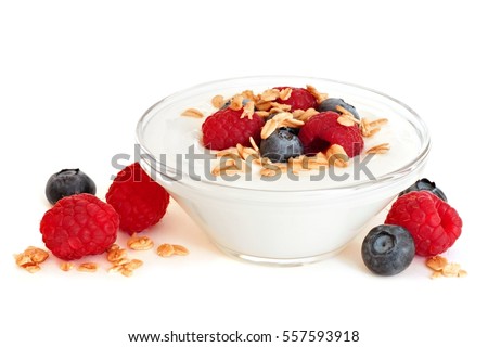 Clear bowl of yogurt with raspberries and blueberries over a white background