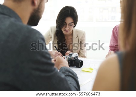 Portrait of attractive young female journalist student making noted in  university coursework using photo files made with camera while waiting for consultation with team leader sitting in classroom