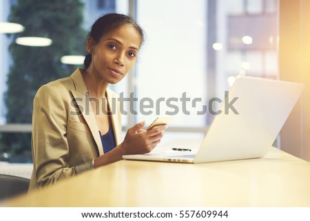 Portrait of official dressed female leader of businnes company preparing for formal meeting with colleagues searching information in internet via smartphone and laptop using wifi in coworking office