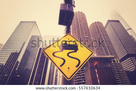 Color toned road sign slippery when wet, Chicago skyscrapers in distance, conceptual picture.