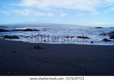 Black Sand Beach, Rocks, Blue Sky, and Clouds with Snow Capped Mountain in Background on the Big Island, Hawaii