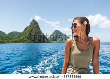 Happy woman cruising towards the deux gros pitons, popular tourist attraction in St Lucia. World Heritage site. Young traveler relaxing on shore excursion boat tour from cruise ship vacation travel. Royalty-Free Stock Photo #557663866
